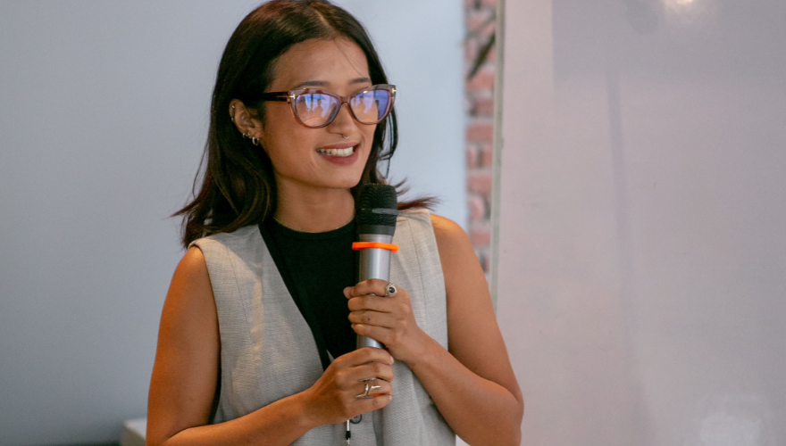 Asian female wearing glasses holding microphone.