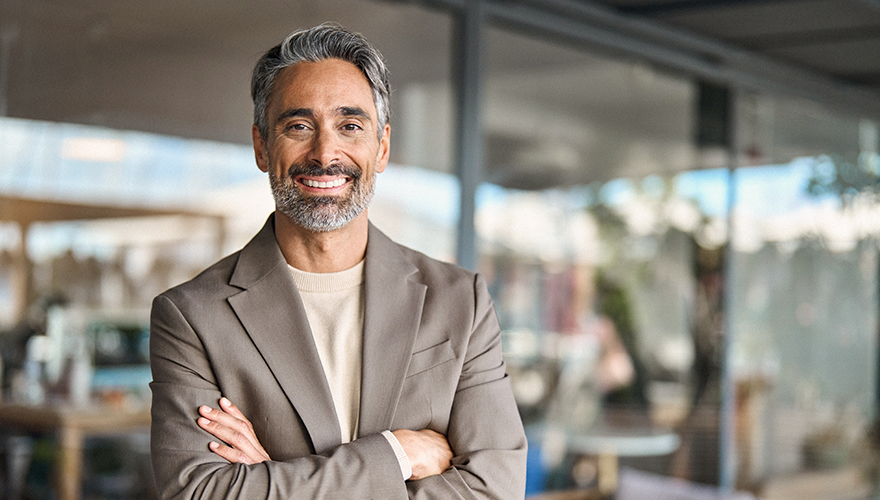 Older man arms folded smiling at the camera