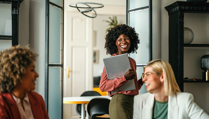 African American woman holding laptop and smiling.