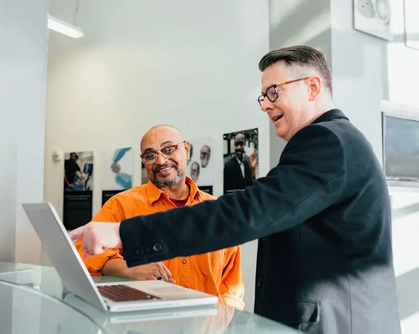 A photo of two men looking at a laptop