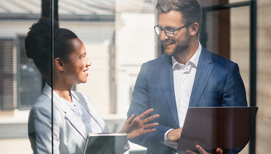 A photo of two colleagues talking in a conference room