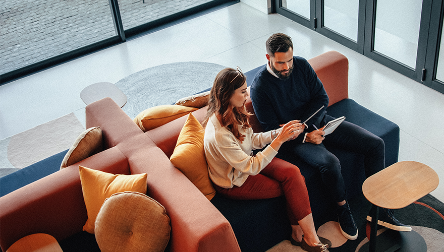 A photo of two coworkers meeting on a couch