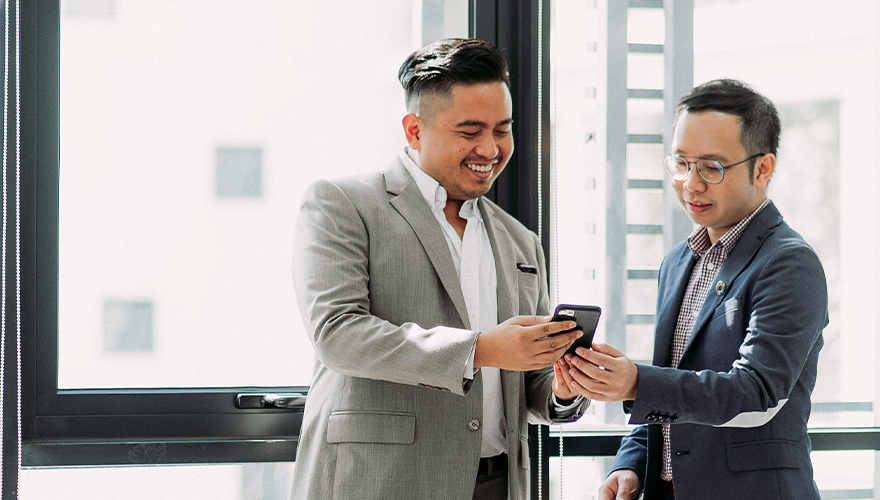 A photo of two colleagues looking at a phone
