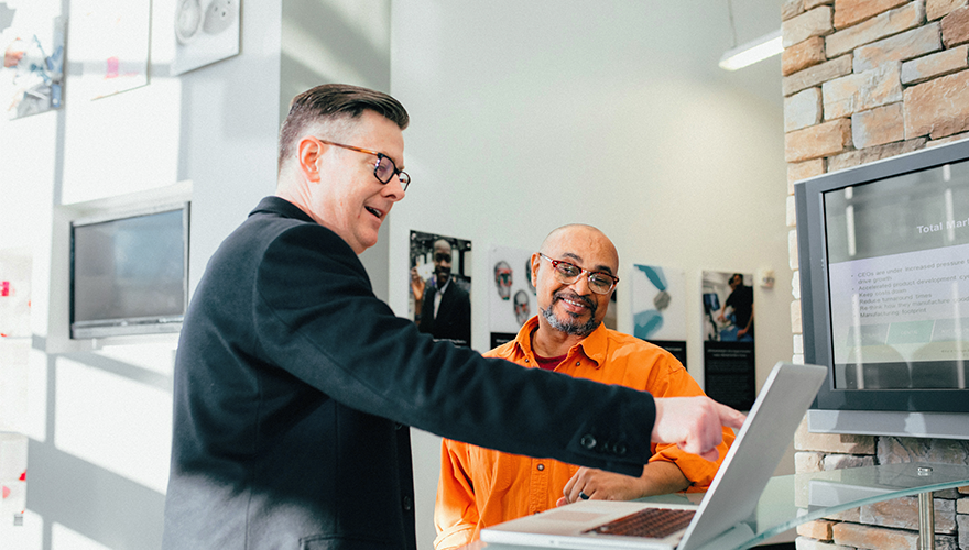 Two men standing at a desk in an office.